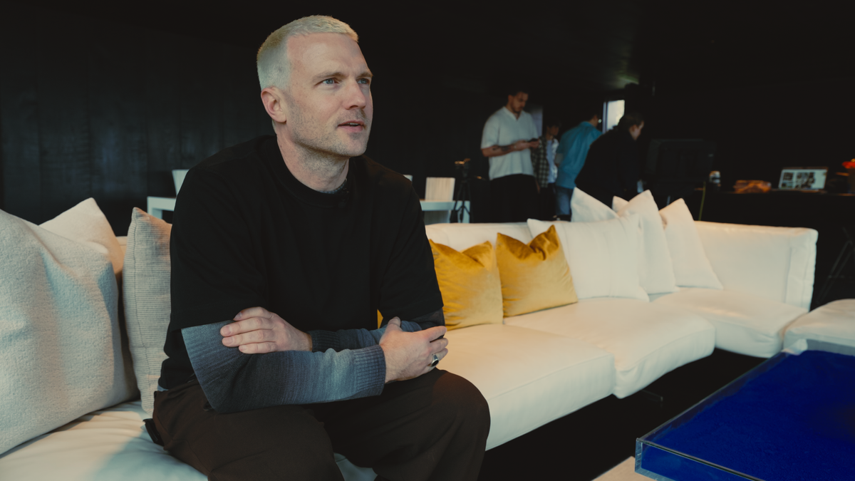 Man sitting on a couch with pillows, looking thoughtfully.