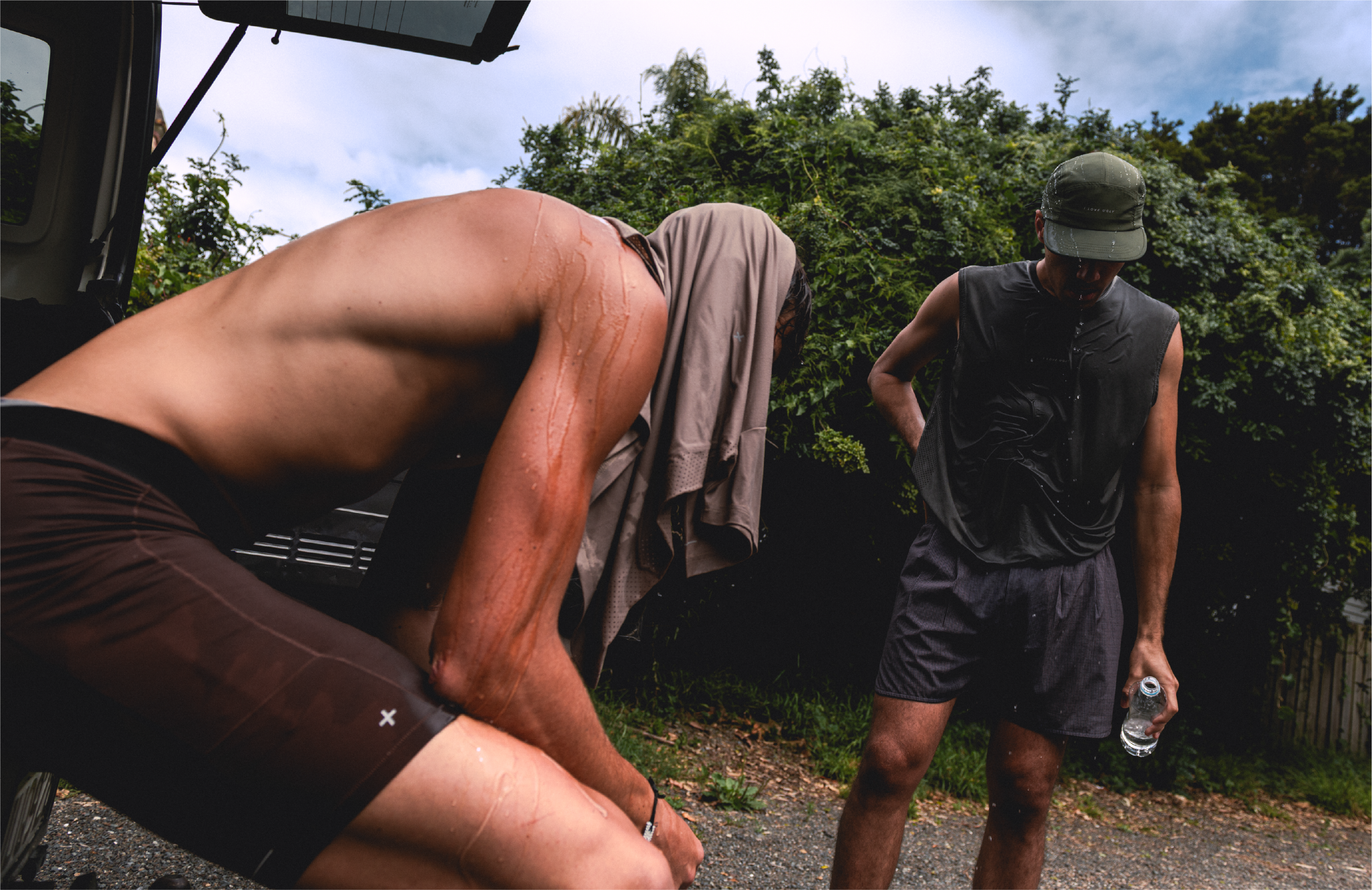 Two men in athletic wear, one sitting, one standing with a water bottle.